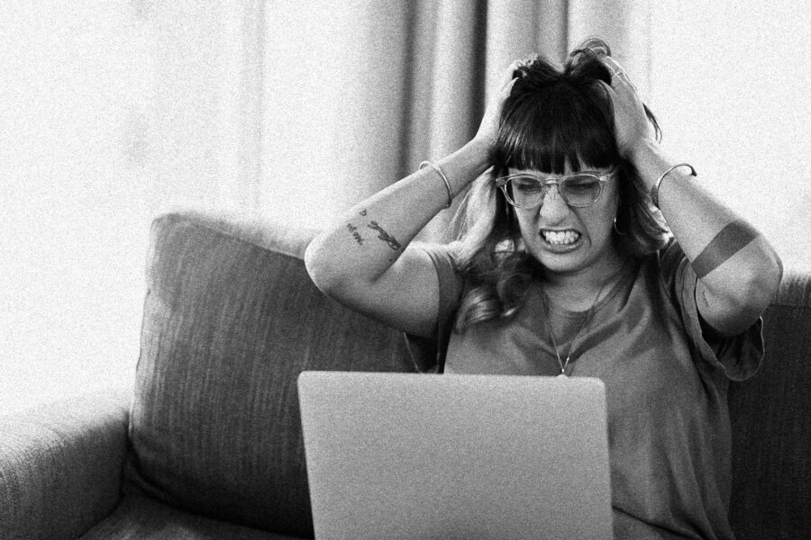 A business owner frustratedly reviewing business marketing strategies on a laptop, surrounded by notes and planning materials, representing clarity and focus in attracting ideal clients.